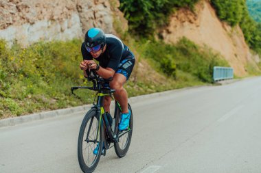 Full length portrait of an active triathlete in sportswear and with a protective helmet riding a bicycle. Selective focus . 