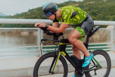 Full length portrait of an active triathlete in sportswear and with a protective helmet riding a bicycle. Selective focus . 