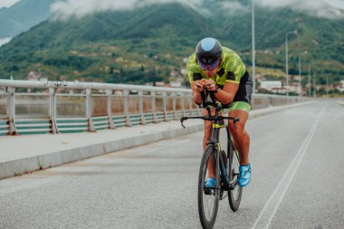 Full length portrait of an active triathlete in sportswear and with a protective helmet riding a bicycle. Selective focus . 
