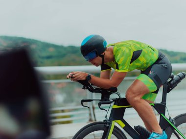 Full length portrait of an active triathlete in sportswear and with a protective helmet riding a bicycle. Selective focus . 