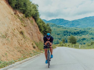 Full length portrait of an active triathlete in sportswear and with a protective helmet riding a bicycle. Selective focus . 
