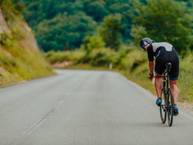Full length portrait of an active triathlete in sportswear and with a protective helmet riding a bicycle. Selective focus . 