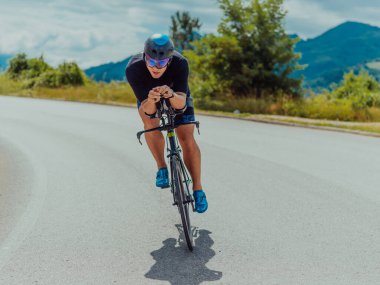 Full length portrait of an active triathlete in sportswear and with a protective helmet riding a bicycle. Selective focus . 