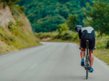 Full length portrait of an active triathlete in sportswear and with a protective helmet riding a bicycle. Selective focus . 
