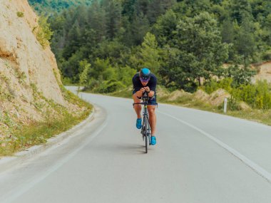 Full length portrait of an active triathlete in sportswear and with a protective helmet riding a bicycle. Selective focus . 