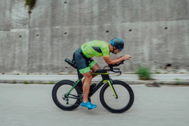 Full length portrait of an active triathlete in sportswear and with a protective helmet riding a bicycle. Selective focus . 