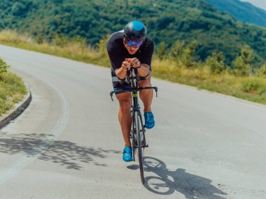 Full length portrait of an active triathlete in sportswear and with a protective helmet riding a bicycle. Selective focus . 