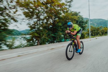 Full length portrait of an active triathlete in sportswear and with a protective helmet riding a bicycle. Selective focus . 
