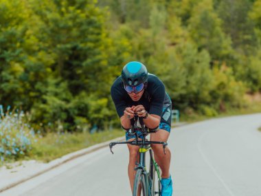 Full length portrait of an active triathlete in sportswear and with a protective helmet riding a bicycle. Selective focus . 