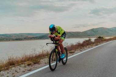 Full length portrait of an active triathlete in sportswear and with a protective helmet riding a bicycle. Selective focus . 