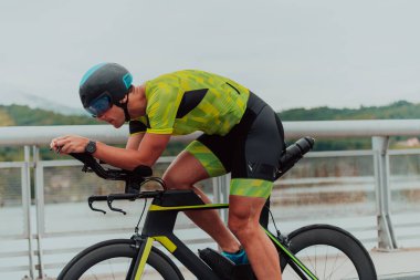 Full length portrait of an active triathlete in sportswear and with a protective helmet riding a bicycle. Selective focus . 