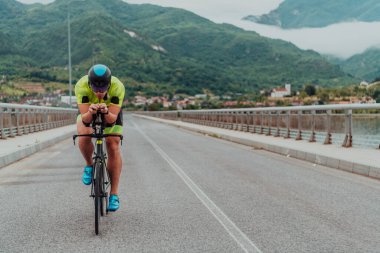 Full length portrait of an active triathlete in sportswear and with a protective helmet riding a bicycle. Selective focus . 