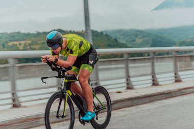 Full length portrait of an active triathlete in sportswear and with a protective helmet riding a bicycle. Selective focus . 