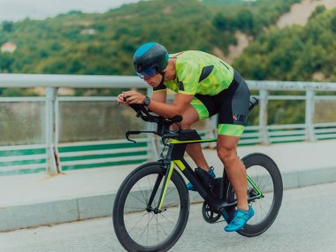 Full length portrait of an active triathlete in sportswear and with a protective helmet riding a bicycle. Selective focus . 