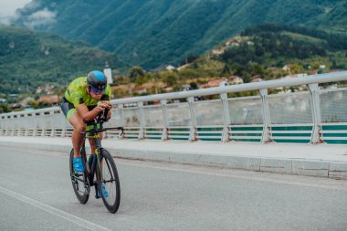 Full length portrait of an active triathlete in sportswear and with a protective helmet riding a bicycle. Selective focus . 
