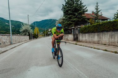 Full length portrait of an active triathlete in sportswear and with a protective helmet riding a bicycle. Selective focus . 