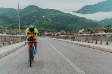 Full length portrait of an active triathlete in sportswear and with a protective helmet riding a bicycle. Selective focus . 