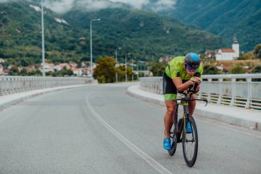 Full length portrait of an active triathlete in sportswear and with a protective helmet riding a bicycle. Selective focus . 