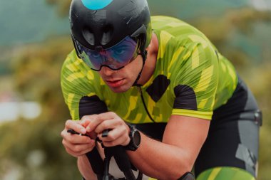 Close up photo of an active triathlete in sportswear and with a protective helmet riding a bicycle. Selective focus. 