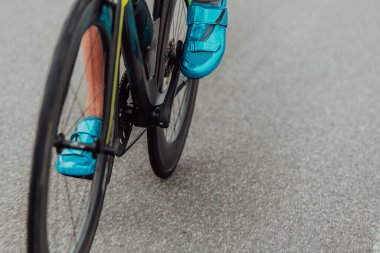 Close up photo of an active triathlete in sportswear and with a protective helmet riding a bicycle. Selective focus. 