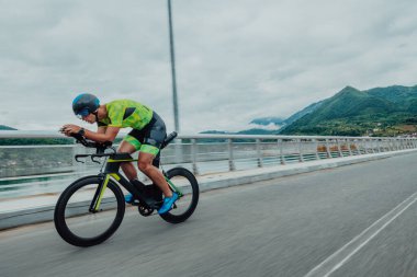 Full length portrait of an active triathlete in sportswear and with a protective helmet riding a bicycle. Selective focus . 