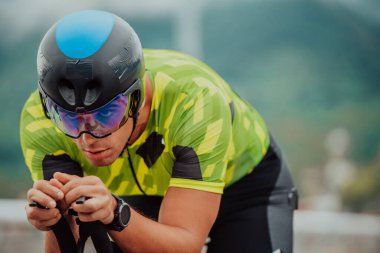 Close up photo of an active triathlete in sportswear and with a protective helmet riding a bicycle. Selective focus. 