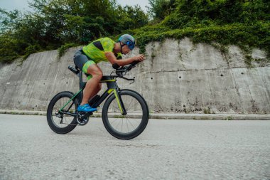 Full length portrait of an active triathlete in sportswear and with a protective helmet riding a bicycle. Selective focus . 