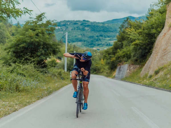Full length portrait of an active triathlete in sportswear and with a protective helmet riding a bicycle. Selective focus . 