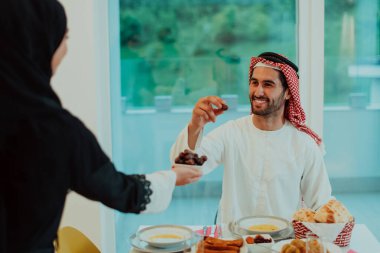 modern çok etnik Müslüman aile bir kase tarihleri paylaşan evde bir ramazan ziyafeti sırasında birlikte iftar yemeği eşliğinde. 