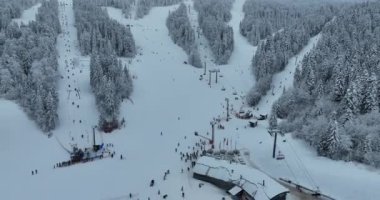 Many skiers and snowboarders skiing down on snowy mountainsides slopes in mountains at ski resort in winter. Family and friends have fun on fresh snow sliding. Bjelasnica mountain. Quality 4k video
