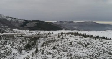 Aerial view of mountain twisted road in the winter. Epic, snowy white winter in the mountains. High rocky mountains and clean road through frozen forest. High quality 4k footage