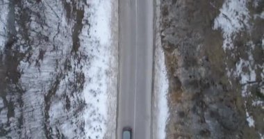 Aerial view of mountain twisted road in the winter. Epic, snowy white winter in the mountains. High rocky mountains and clean road through frozen forest. High quality 4k footage
