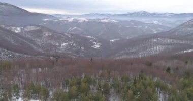 Aerial view of mountain twisted road in the winter. Epic, snowy white winter in the mountains. High rocky mountains and clean road through frozen forest. High quality 4k footage