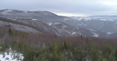 Aerial view of mountain twisted road in the winter. Epic, snowy white winter in the mountains. High rocky mountains and clean road through frozen forest. High quality 4k footage