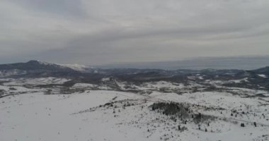 Aerial view of mountain twisted road in the winter. Epic, snowy white winter in the mountains. High rocky mountains and clean road through frozen forest. High quality 4k footage