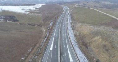 Aerial view of mountain twisted road in the winter. Epic, snowy white winter in the mountains. High rocky mountains and clean road through frozen forest. High quality 4k footage