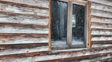 Splendid mountain winter landscape with secluded small wooden alpine cottage among the fir trees fully covered by snow during snow fall. Hi quality 4K slow motion footage. 