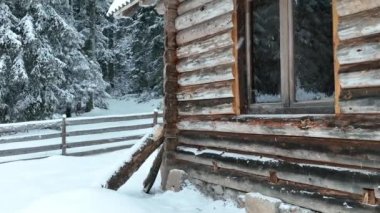 Splendid mountain winter landscape with secluded small wooden alpine cottage among the fir trees fully covered by snow during snow fall. Hi quality 4K slow motion footage. 