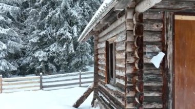 Splendid mountain winter landscape with secluded small wooden alpine cottage among the fir trees fully covered by snow during snow fall. Hi quality 4K slow motion footage. 