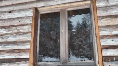 Splendid mountain winter landscape with secluded small wooden alpine cottage among the fir trees fully covered by snow during snow fall. Hi quality 4K slow motion footage. 