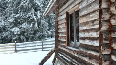 Splendid mountain winter landscape with secluded small wooden alpine cottage among the fir trees fully covered by snow during snow fall. Hi quality 4K slow motion footage. 