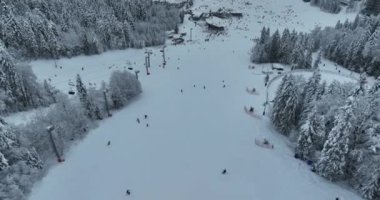 Many skiers and snowboarders skiing down on snowy mountainsides slopes in mountains at ski resort in winter. Family and friends have fun on fresh snow sliding. Bjelasnica mountain. Quality 4k video