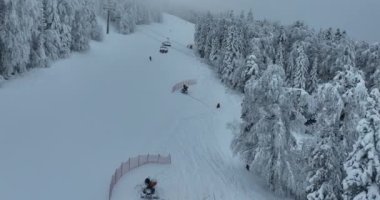 Many skiers and snowboarders skiing down on snowy mountainsides slopes in mountains at ski resort in winter. Family and friends have fun on fresh snow sliding. Bjelasnica mountain. Quality 4k video