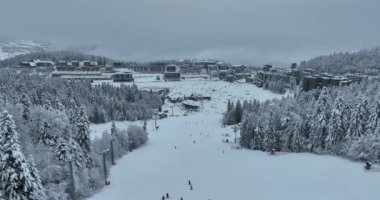 Many skiers and snowboarders skiing down on snowy mountainsides slopes in mountains at ski resort in winter. Family and friends have fun on fresh snow sliding. Bjelasnica mountain. Quality 4k video