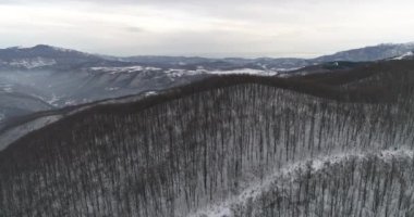 Aerial view of mountain twisted road in the winter. Epic, snowy white winter in the mountains. High rocky mountains and clean road through frozen forest. High quality 4k footage