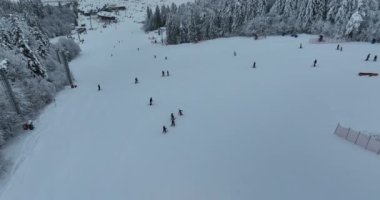 Many skiers and snowboarders skiing down on snowy mountainsides slopes in mountains at ski resort in winter. Family and friends have fun on fresh snow sliding. Bjelasnica mountain. Quality 4k video