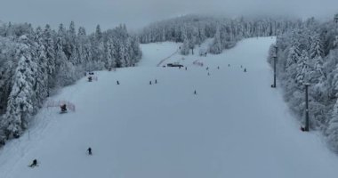Many skiers and snowboarders skiing down on snowy mountainsides slopes in mountains at ski resort in winter. Family and friends have fun on fresh snow sliding. Bjelasnica mountain. Quality 4k video