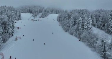 Many skiers and snowboarders skiing down on snowy mountainsides slopes in mountains at ski resort in winter. Family and friends have fun on fresh snow sliding. Bjelasnica mountain. Quality 4k video