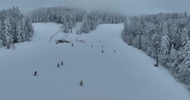Many skiers and snowboarders skiing down on snowy mountainsides slopes in mountains at ski resort in winter. Family and friends have fun on fresh snow sliding. Bjelasnica mountain. Quality 4k video