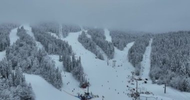 Many skiers and snowboarders skiing down on snowy mountainsides slopes in mountains at ski resort in winter. Family and friends have fun on fresh snow sliding. Bjelasnica mountain. Quality 4k video